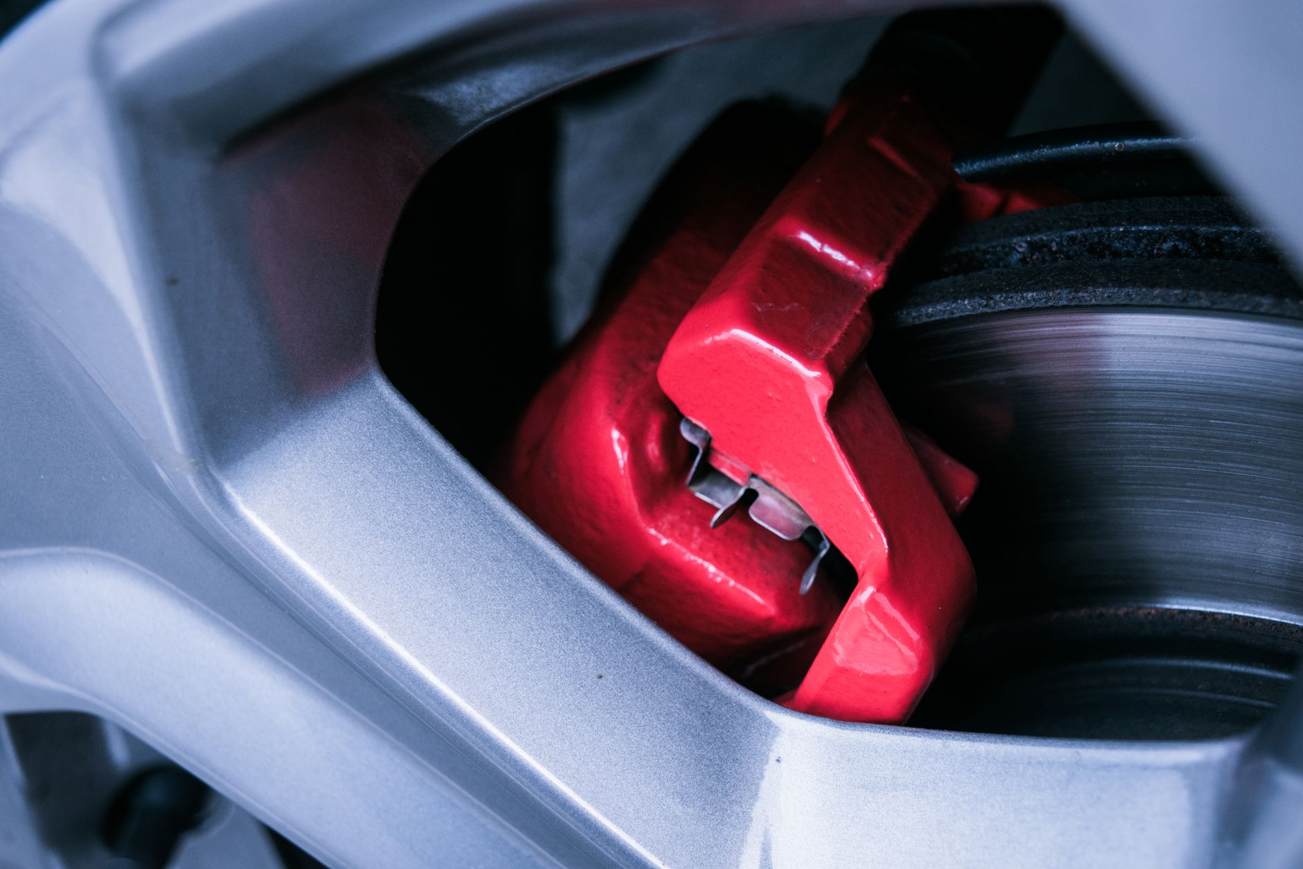 Close-up of a silver alloy wheel with a red brake caliper and brake disc behind it
