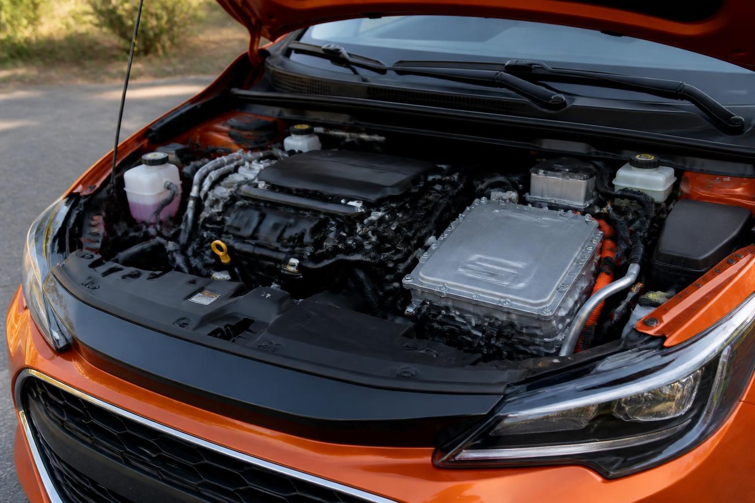 Open orange car engine bay with combustion engine, silver electric module, and orange high-voltage cables