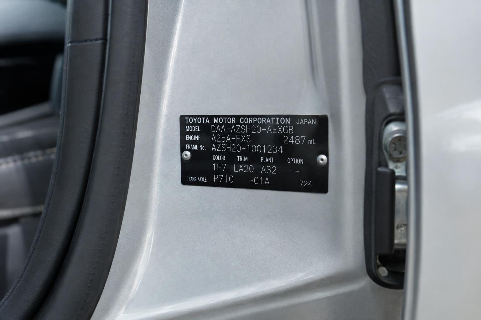 Toyota AZSH20 identification plate riveted to a silver car's door jamb.