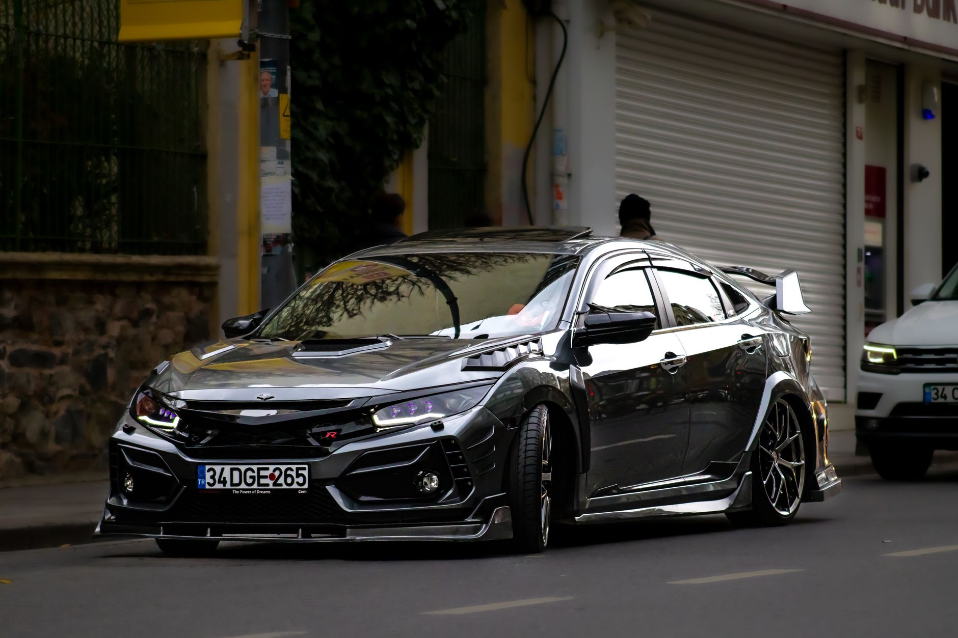 Black Honda Civic Type R driving on a city street, viewed from the front side.