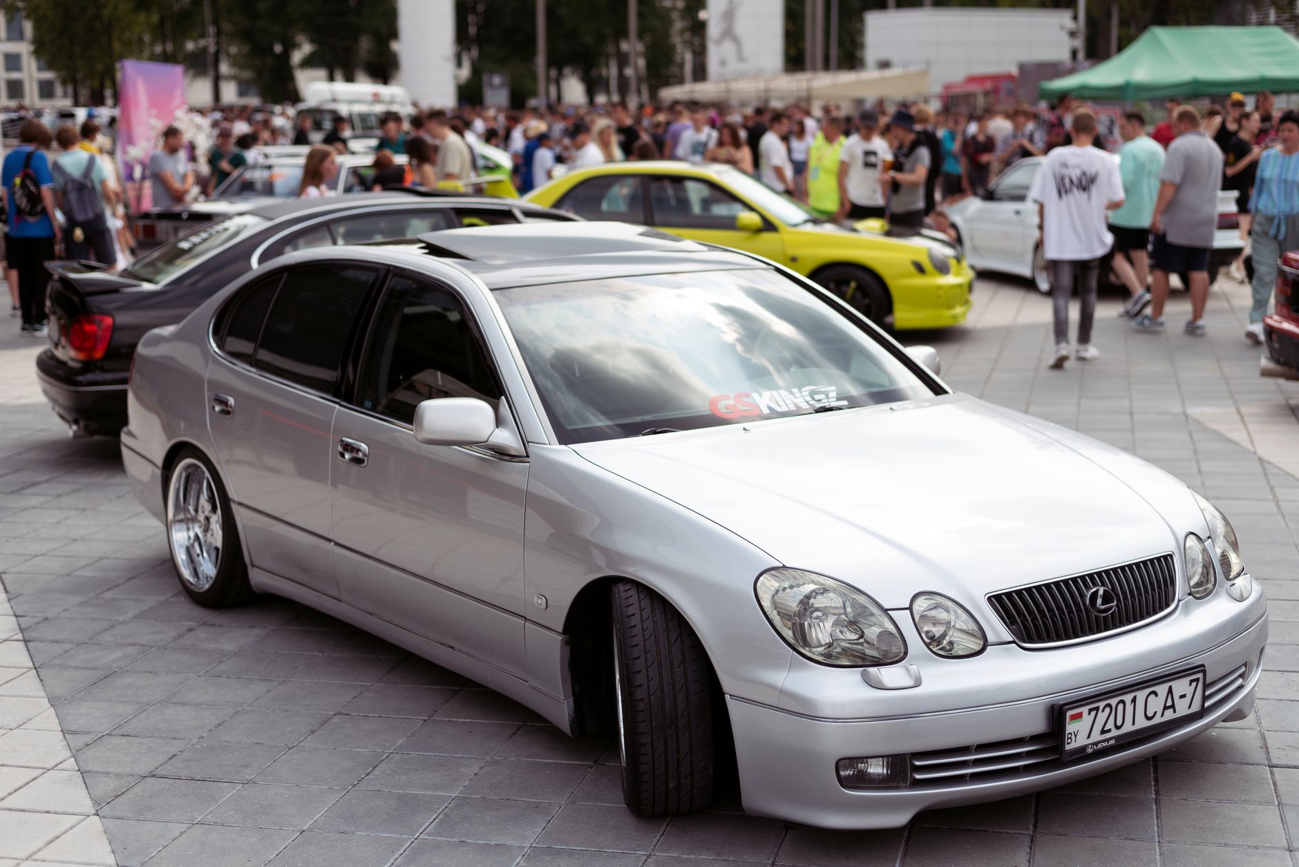 Silver Lexus GS four-door sedan parked at a crowded outdoor car gathering.