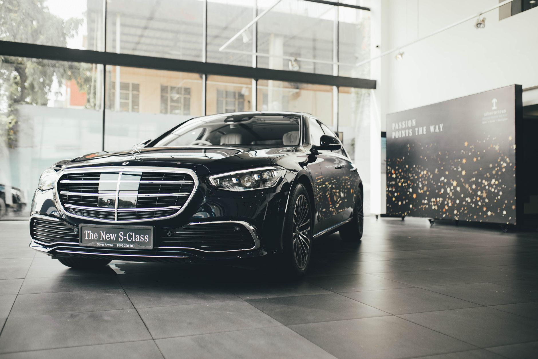 Dark Mercedes-Benz S-Class sedan viewed from the front quarter in a bright showroom
