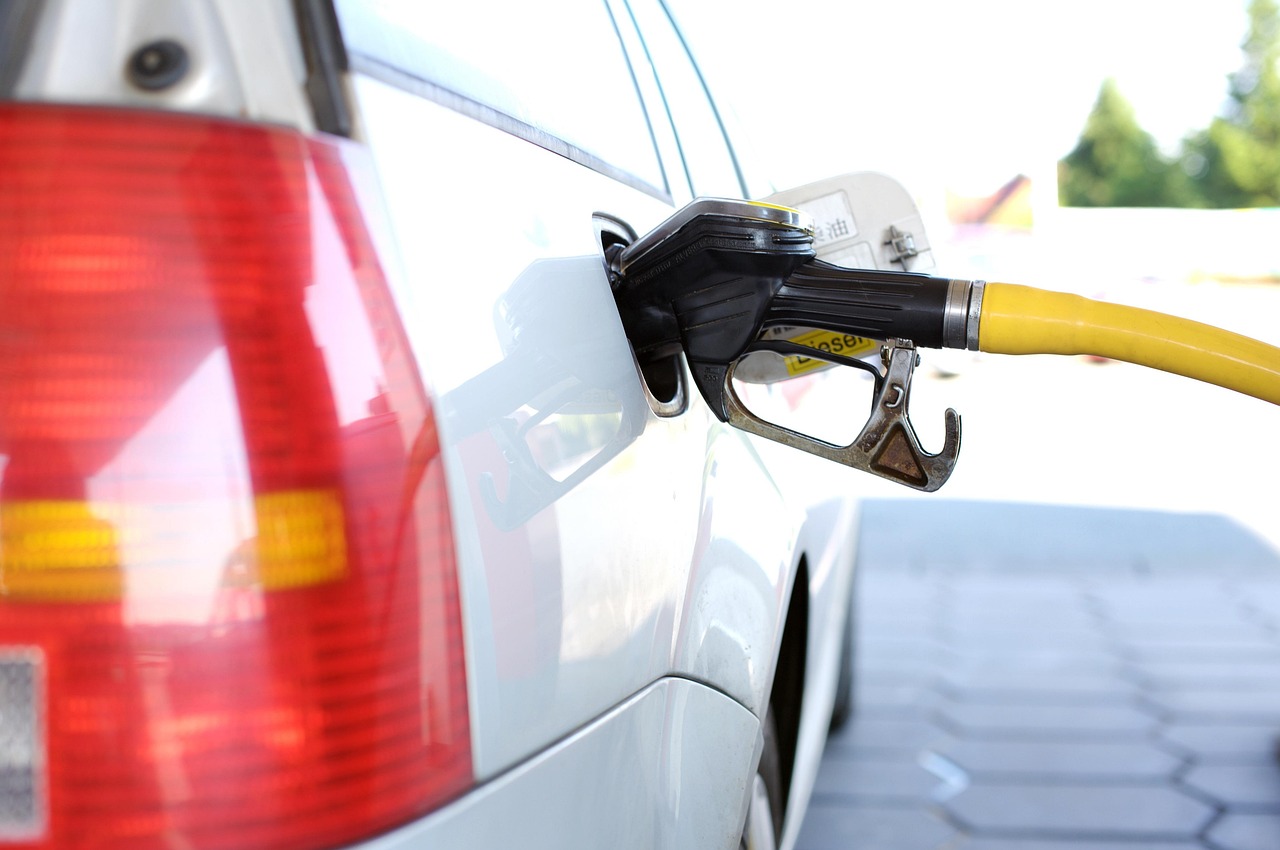 Yellow fuel nozzle inserted into the fuel port of a silver car.