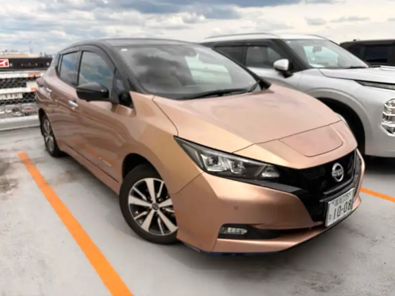 Gold second-generation Nissan Leaf parked in a rooftop car park, shown from the front left.