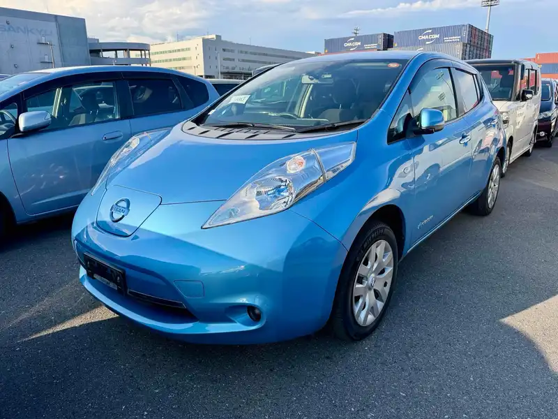 Blue first-generation Nissan Leaf parked in a vehicle storage lot.