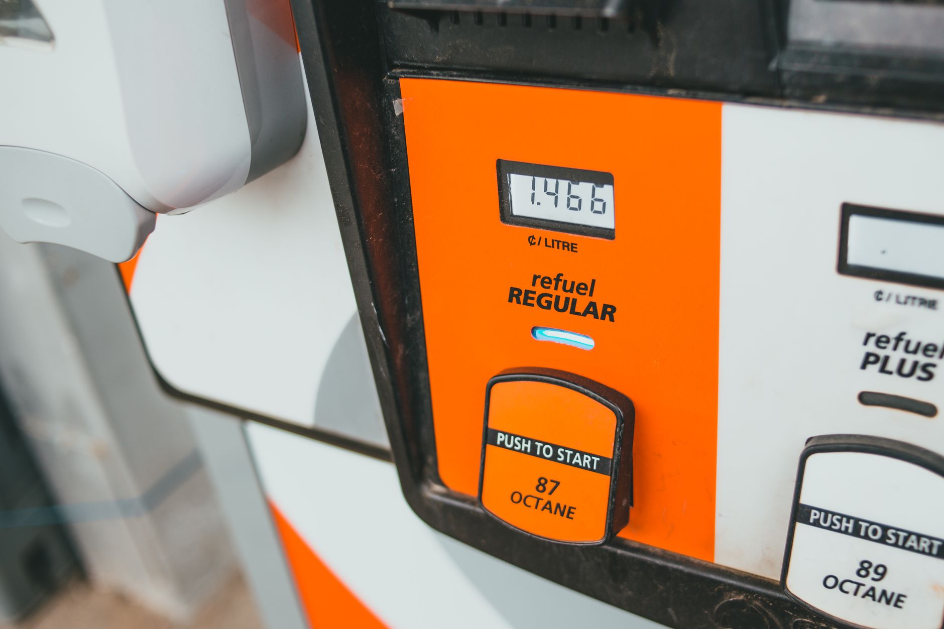 Close-up of a petrol pump with orange panel, fuel grade buttons, and a digital price display