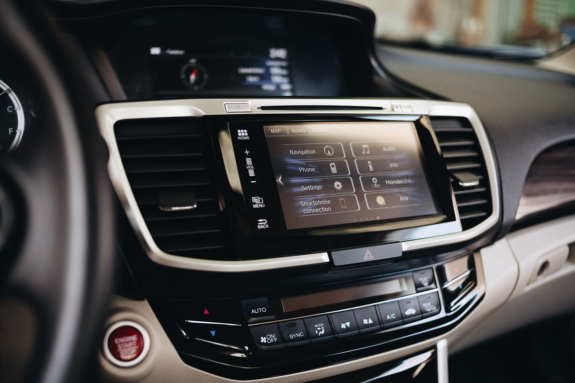 Modern car center console with touchscreen display, air vents, climate controls, and start button
