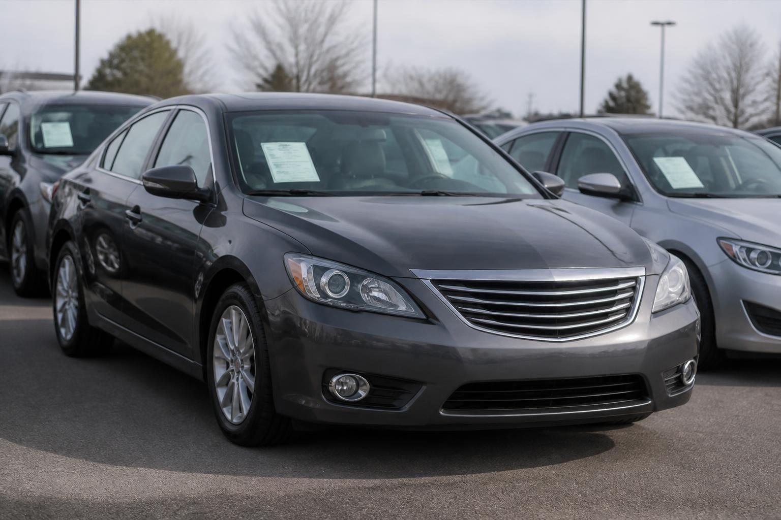 Dark gray sedan parked among other labeled cars on a dealership lot