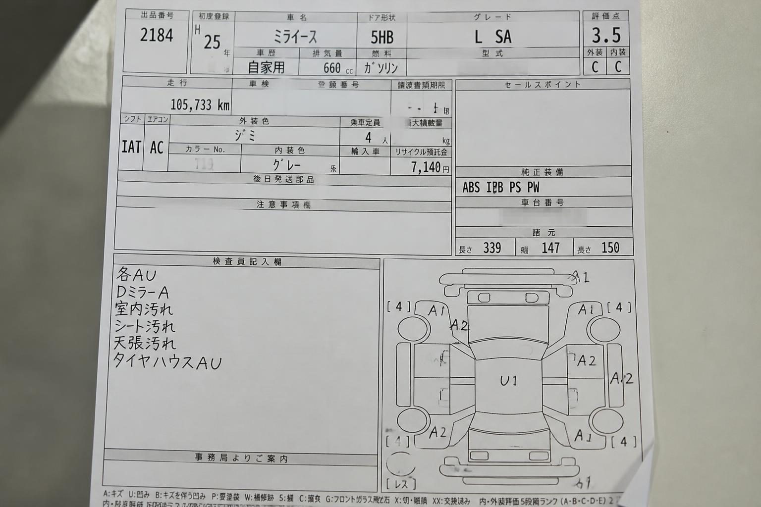 Japanese used-car auction sheet with grade 3.5, mileage, notes, and damage diagram on a desk