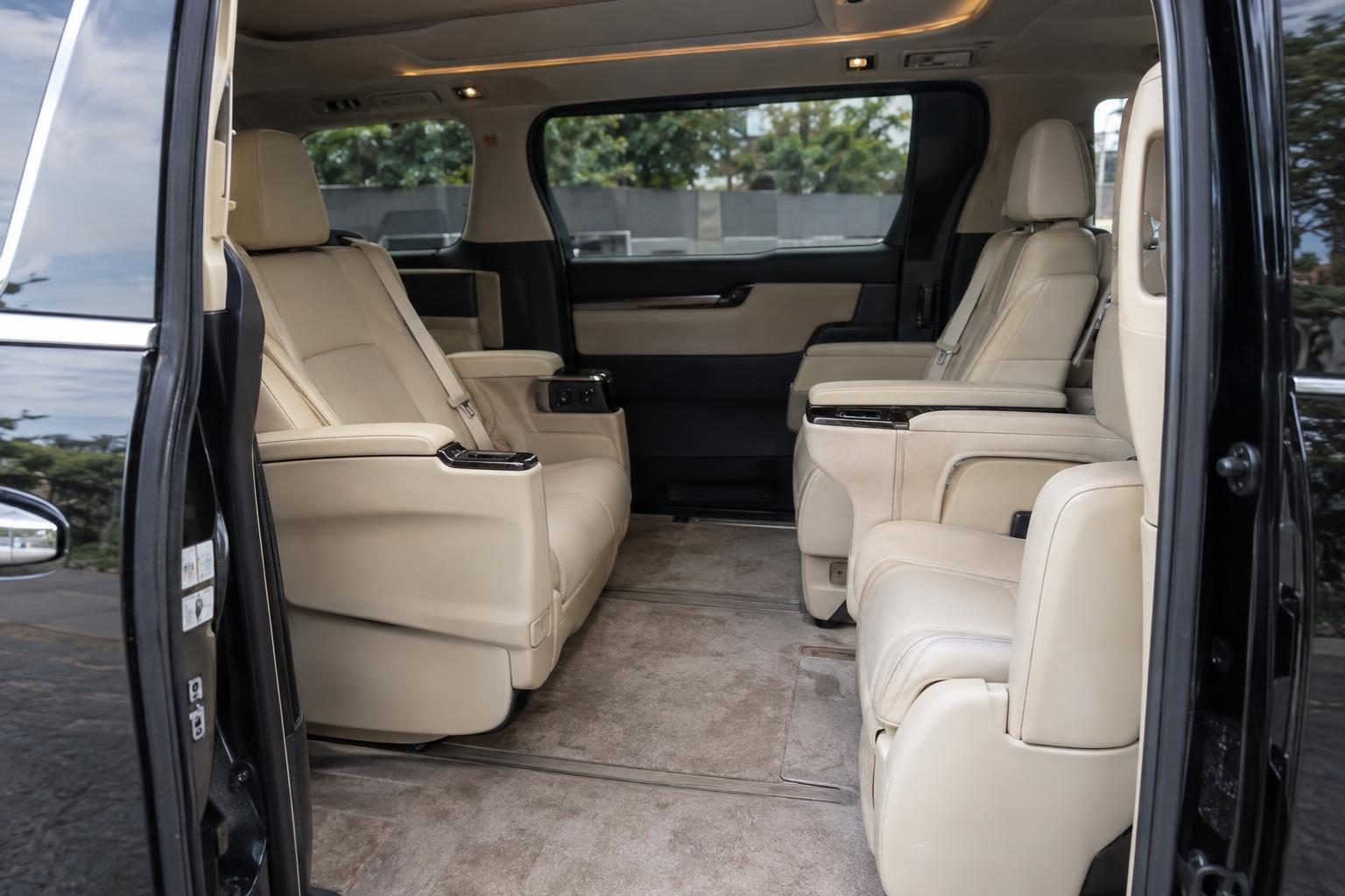 Cream leather second-row captain's chairs and a centre walk-through aisle in a Toyota Alphard.