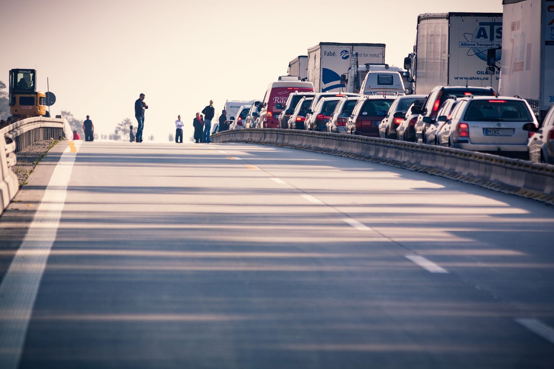 Cars and trucks queued bumper-to-bumper on a sunlit city roadway.