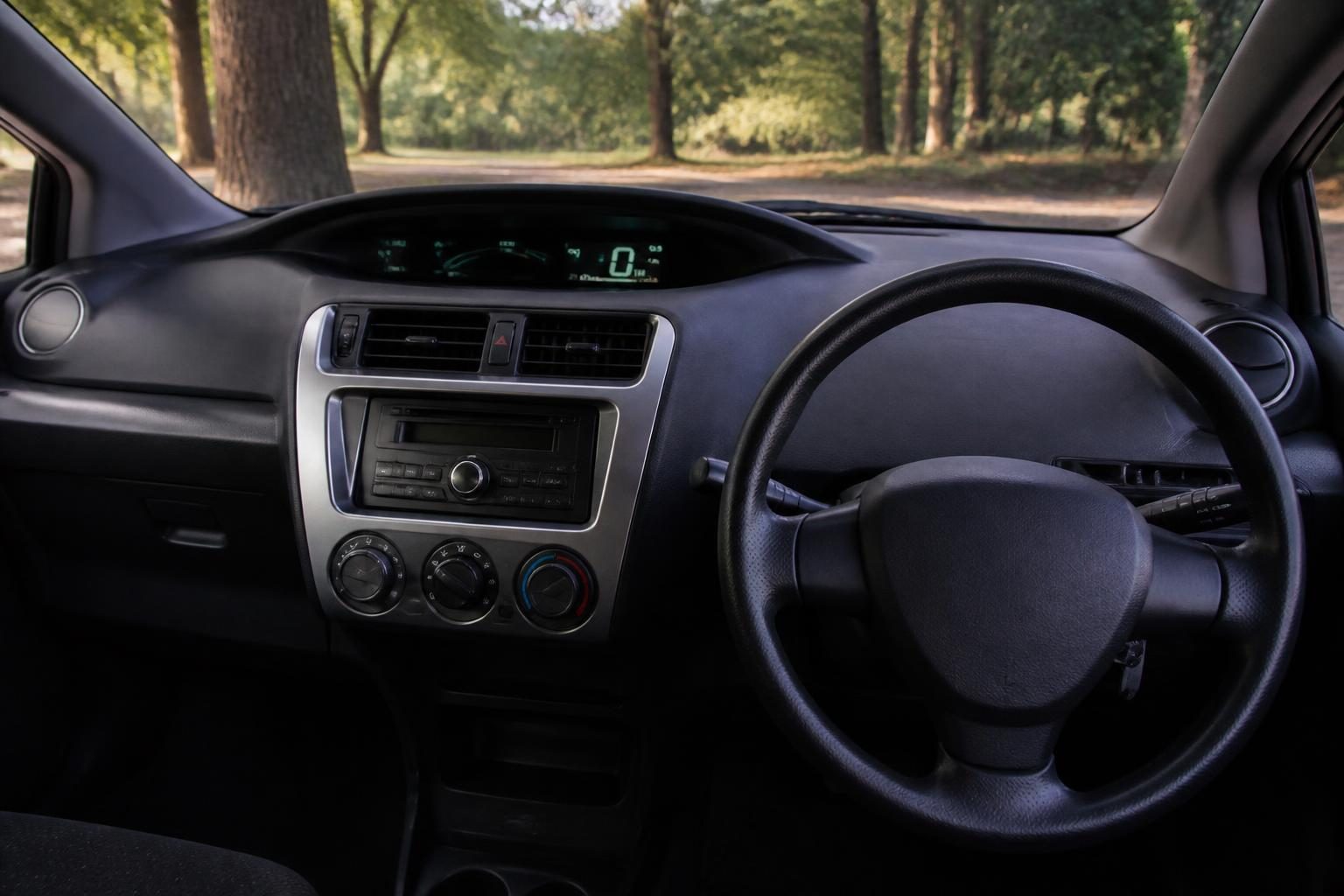 Right-hand-drive hatchback dashboard with centre digital display, stereo and three climate-control dials.