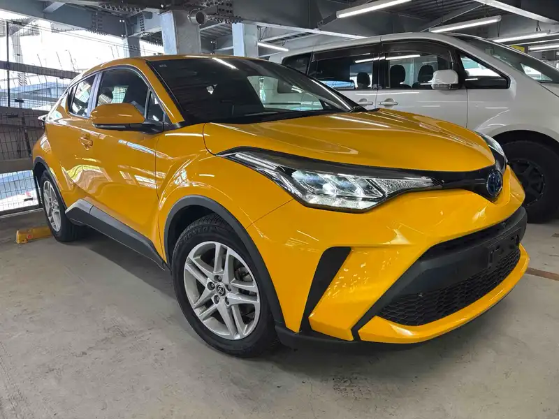 Yellow first-generation facelift Toyota C-HR viewed from the front left indoors.
