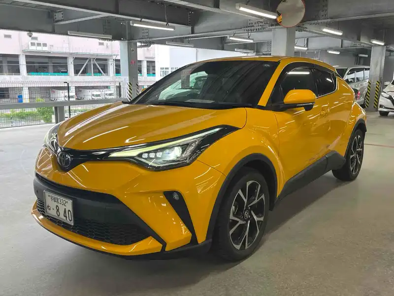 Yellow first-generation facelift Toyota C-HR parked in a covered garage.