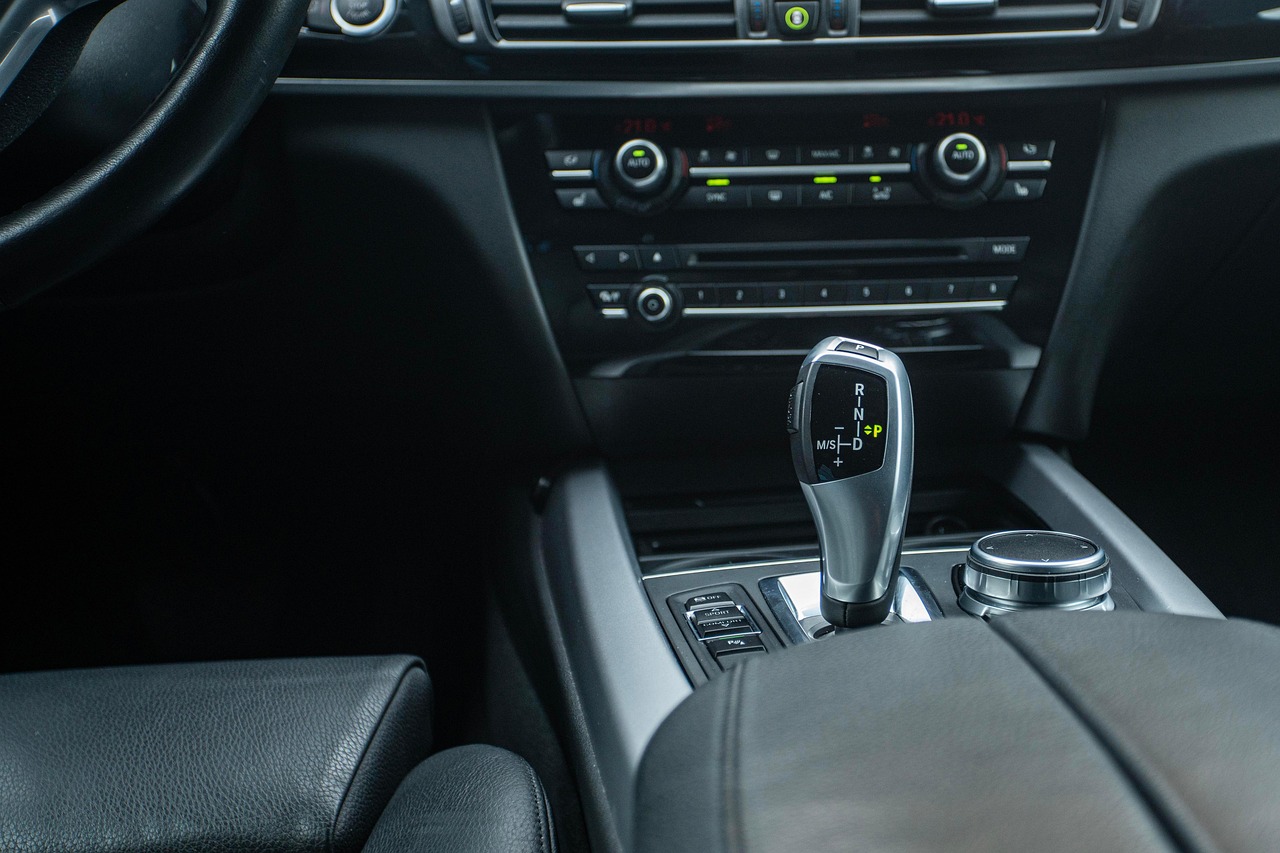Close-up of a black leather car interior with gear selector, control dial, and climate controls