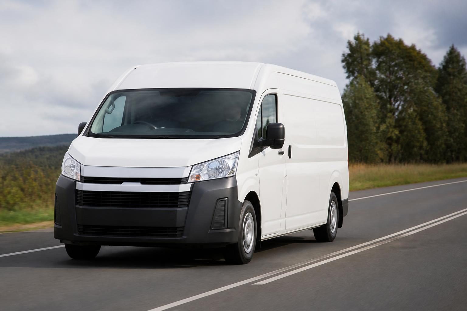 White high-roof cargo van driving on a paved rural two-lane road.