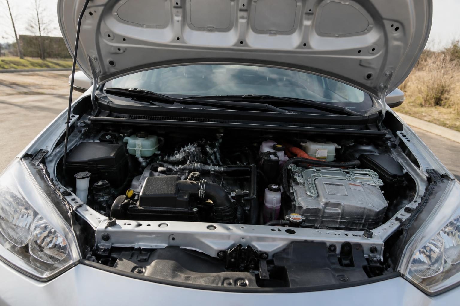 Open car hood showing a hybrid engine bay with orange high-voltage cables and metal inverter unit